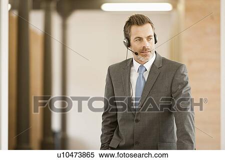 Stock Photography - Businessman wearing headset in office. Fotosearch