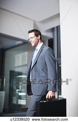 Stock Image - Businessman with briefcase in office. Fotosearch