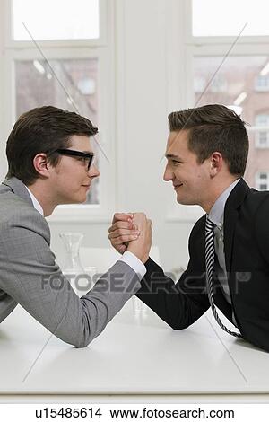 Picture - Businessmen arm wrestling in office. Fotosearch