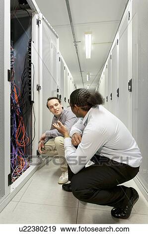 Stock Photo - Businessmen examining wires in server. Fotosearch