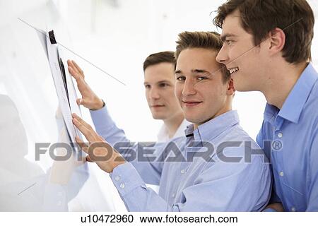 Businessmen reading together in office View Large Photo Image Stock Image - Businessmen reading together in office. Fotosearch