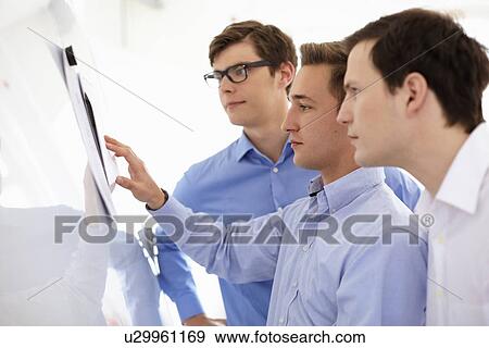 Businessmen reading together in office View Large Photo Image Stock Photo - Businessmen reading together in office. Fotosearch