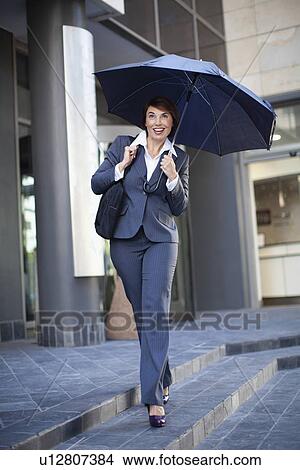 Businesswoman carrying umbrella outdoors View Large Photo Image Picture - Businesswoman carrying umbrella outdoors. Fotosearch