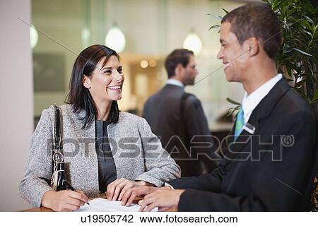 Stock Image - Businesswoman checking into hotel. Fotosearch