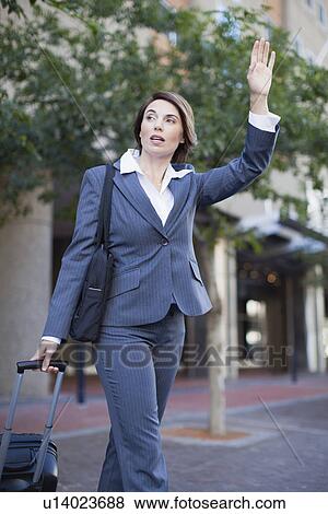 Stock Photo - Businesswoman hailing taxi on street. Fotosearch