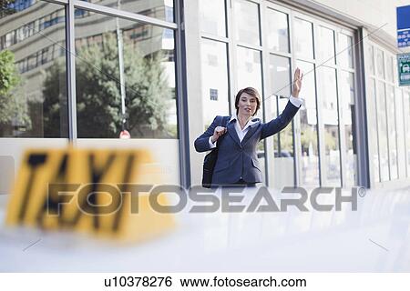 Stock Photograph - Businesswoman hailing taxi on street. Fotosearch
