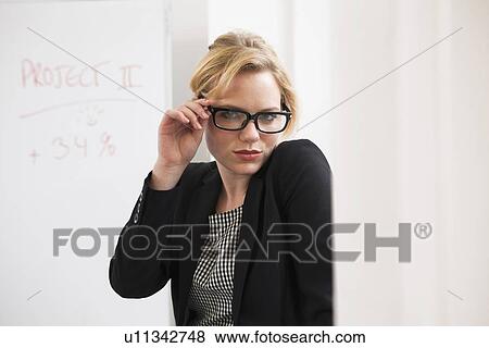 Businesswoman holding glasses in office View Large Photo Image Stock Photo - Businesswoman holding glasses in office. Fotosearch