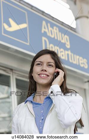 Stock Photo - Businesswoman on cell phone at airport. Fotosearch