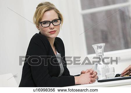 Businesswoman sitting at desk View Large Photo Image Stock Photograph - Businesswoman sitting at desk. Fotosearch