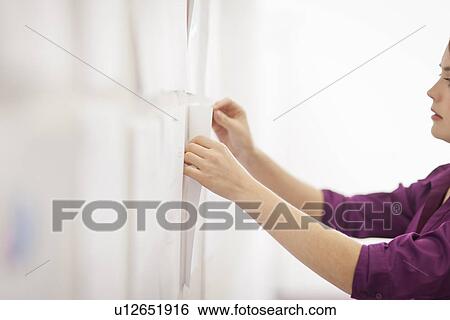 Stock Photograph - Businesswoman tacking up signs in office. Fotosearch
