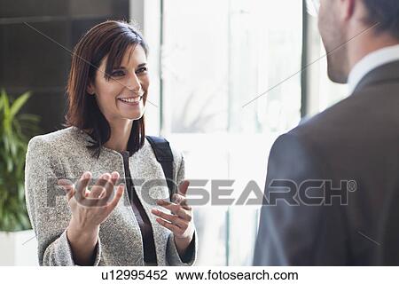 Stock Image - Businesswoman talking to colleague. Fotosearch