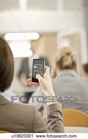 Stock Image - Businesswoman using cell phone in office. Fotosearch