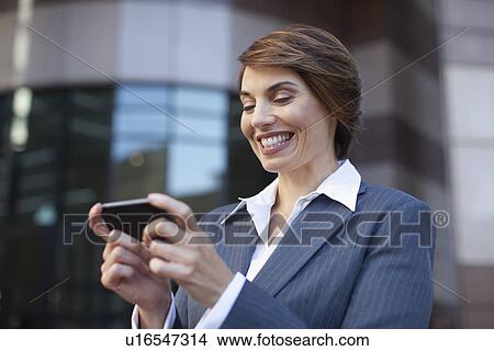 Picture - Businesswoman using cell phone outdoors. Fotosearch