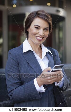 Stock Photo - Businesswoman using cell phone outdoors. Fotosearch