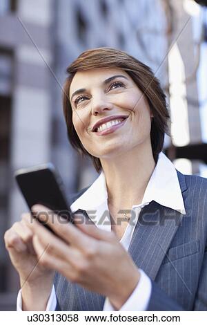 Stock Photo - Businesswoman using cell phone outdoors. Fotosearch