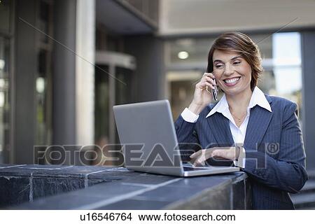 Picture - Businesswoman using laptop outdoors. Fotosearch