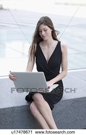 Stock Image - Businesswoman using laptop outdoors. Fotosearch