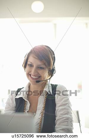 Businesswoman wearing headset at desk View Large Photo Image Stock Photograph - Businesswoman wearing headset at desk. Fotosearch