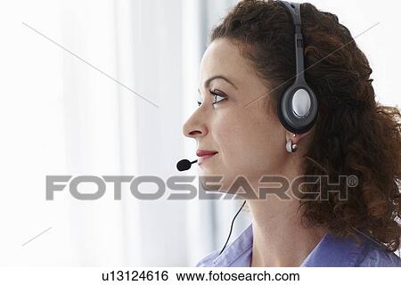 Businesswoman wearing headset in office View Large Photo Image Stock Photograph - Businesswoman wearing headset in office. Fotosearch