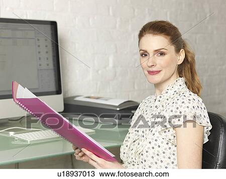 Stock Image - Businesswoman with folder at desk. Fotosearch