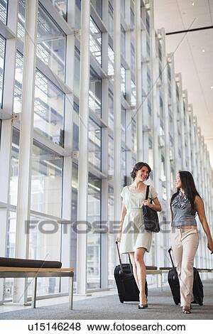 Businesswomen rolling luggage in hallway View Large Photo Image Stock Photo - Businesswomen rolling luggage in hallway. Fotosearch