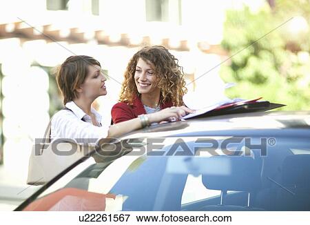 Businesswomen talking at car outdoors View Large Photo Image Stock Photo - Businesswomen talking at car outdoors. Fotosearch