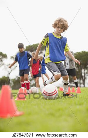 Stock Image - Childrens soccer team training on pitch. Fotosearch