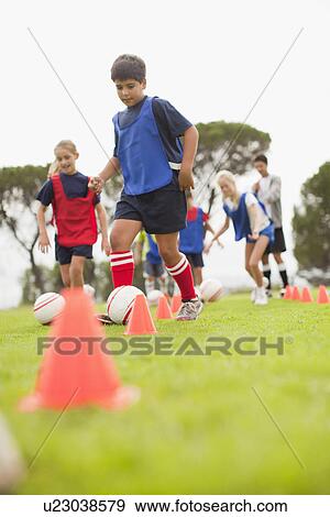 Stock Photo - Childrens soccer team training on pitch. Fotosearch