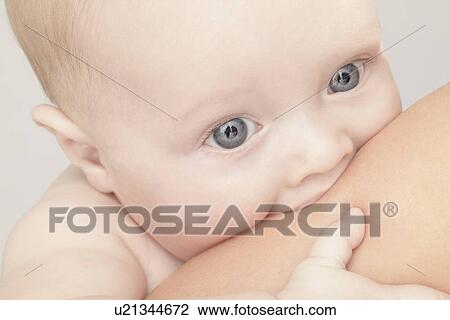 Stock Image - Close up of baby girl chewing on hand. Fotosearch