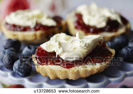 Stock Image - Close up of sliced scone with jam. Fotosearch