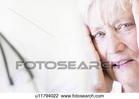 Stock Image - Close up of woman holding her head. Fotosearch
