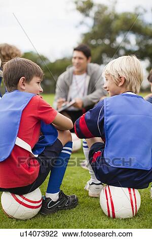 Stock Image - Coach talking to childrens soccer team. Fotosearch