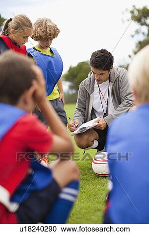 Stock Image - Coach talking to childrens soccer team. Fotosearch