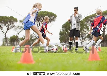 Stock Image - Coach training childrens soccer team. Fotosearch