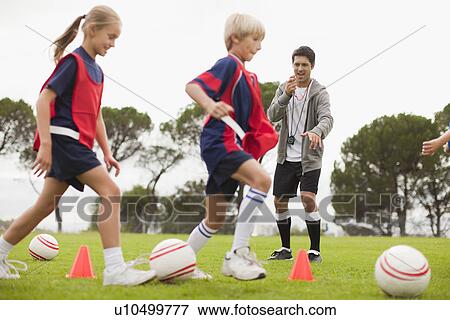 Stock Photo - Coach training childrens soccer team. Fotosearch