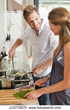 Stock Image - Couple cooking together in kitchen. Fotosearch