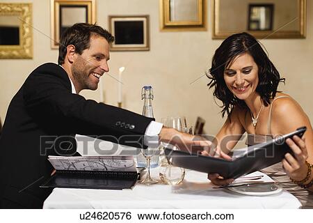 Couple examining menus in restaurant View Large Photo Image Stock Photograph - Couple examining menus in restaurant. Fotosearch