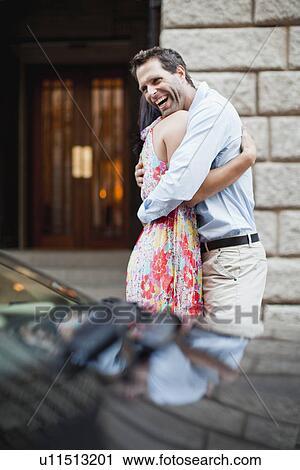 Couple hugging by car on city street View Large Photo Image Stock Image - Couple hugging by car on city street. Fotosearch