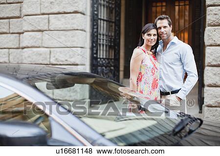 Couple hugging by car on city street View Large Photo Image Stock Photo - Couple hugging by car on city street. Fotosearch