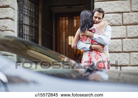 Stock Photography - Couple hugging by car on city street. Fotosearch