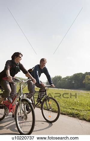 Couple riding bicycles on rural road View Large Photo Image Stock Photo - Couple riding bicycles on rural road. Fotosearch