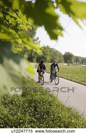 Couple riding bicycles on rural road View Large Photo Image Stock Photography - Couple riding bicycles on rural road. Fotosearch