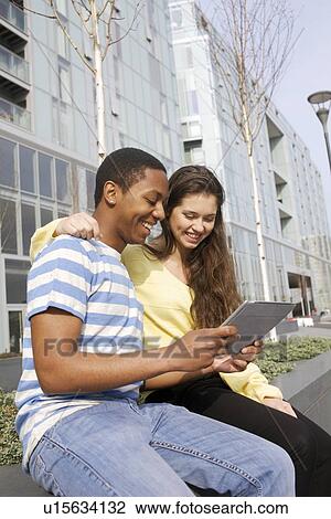 Stock Image - Couple using tablet computer on street. Fotosearch