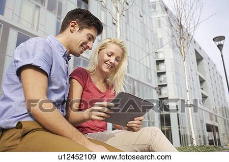 Couple using tablet computer on street View Large Photo Image Stock Photo - Couple using tablet computer on street. Fotosearch