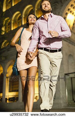 Couple walking on city street at night View Large Photo Image Stock Image - Couple walking on city street at night. Fotosearch