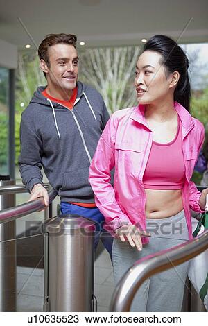 Stock Image - Couple walking through turnstile. Fotosearch