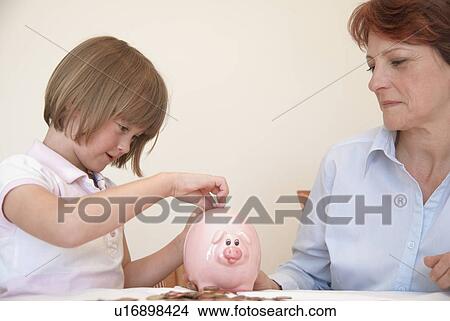 Daughter putting money in piggy bank View Large Photo Image Picture - Daughter putting money in piggy bank. Fotosearch