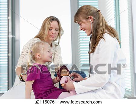 Stock Image - Doctor examining girls doll in office. Fotosearch