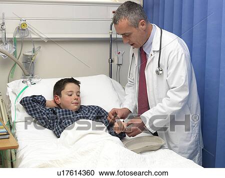 Stock Image - Doctor examining patient in hospital. Fotosearch