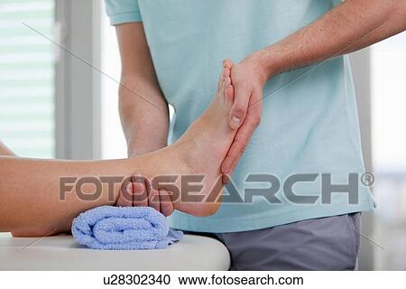 Stock Image - Doctor examining womans feet in office. Fotosearch